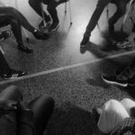 Black and white photo of a support group session indoors with diverse participants.